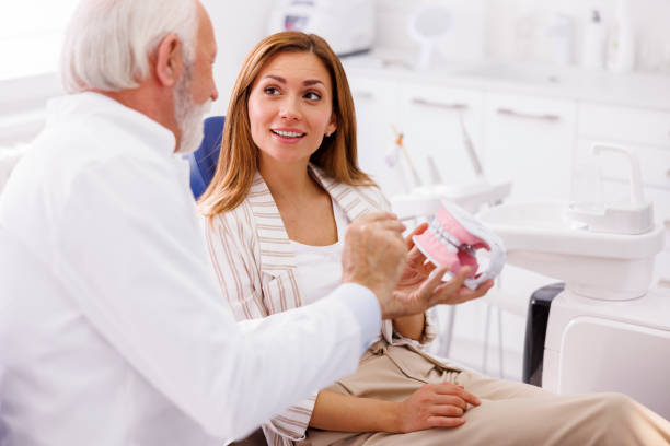 istock Dentist explaining procedure to patient on plastic jaw model 1392724779