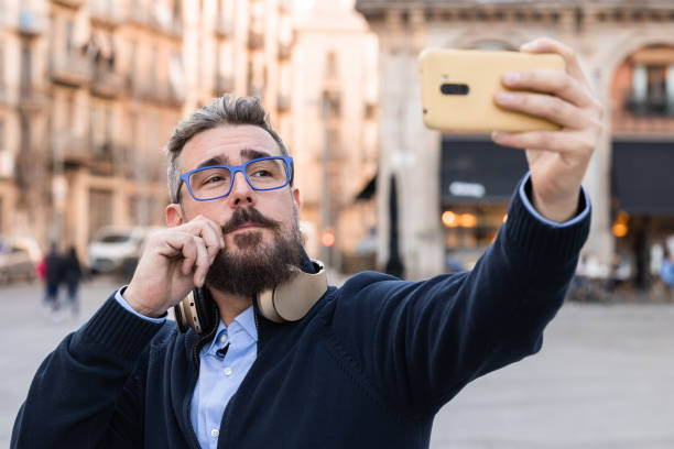 istock Adult man taking selfie while touching his mustache outdoors 1392728568