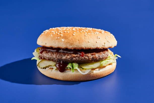istock Beef burger blue background with hard shadow. American junk food minimal style. Hamburger trendy style.  Simple burger colour background. 1392734377