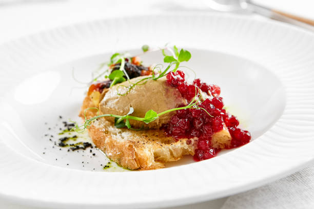 istock Chicken liver pate on crispy bread with red currant jam and micro green. Bruschetta with chicken pate in white plate. Delicious appetizer - foie gras on toast. Liver pate with jam in rustic style. 1392737162