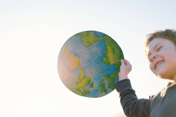istock Little boy holding planet in hands against green spring background 1392737227