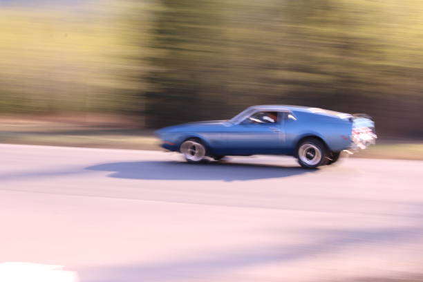 Intentional blurred motion of a blue car driving on an asphalt road.