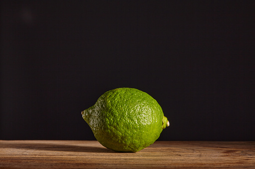 A whole lime on a wooden chopping board