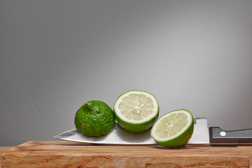 Sliced limes on a wooden chopping board on a knife