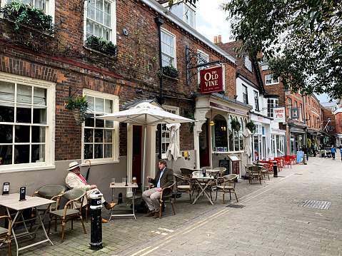 Street view of Winchester old town Hampshire England cozy brick restaurant and hotel the Old Vine charming house. Great Minster street, the Square