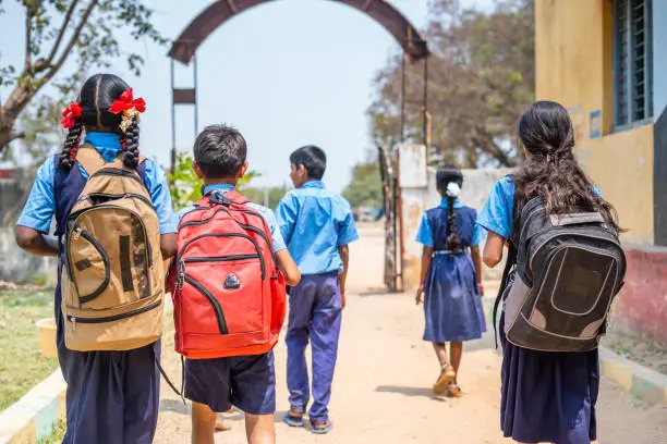 Back view shot of group of teenager kids in uniform going home from school after classes - concept of education, learning and childhood growth.