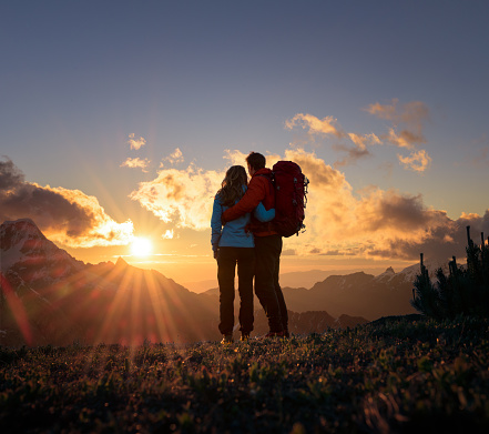 In love couple watching the sunset while hiking in the mountains