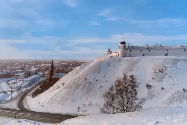 View of Tobolsk (Russia) - an ancient city lying under the mountain and on the mountain in a frosty winter evening. A haze spreads over the city. The houses of the townspeople, churches are visible