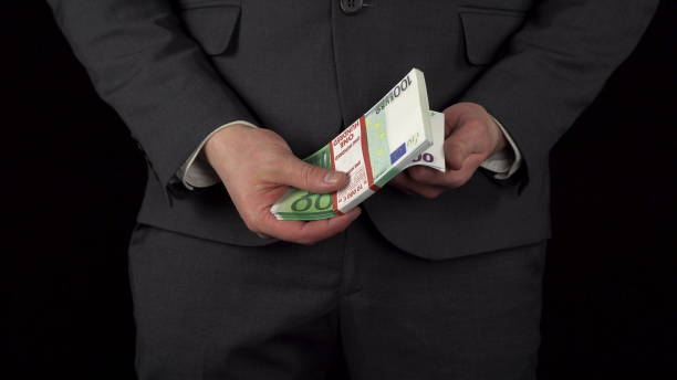 un jeune homme d’affaires en costume sort un paquet d’euros de sa poche et le tient dans ses mains. la taille d’un homme en gros plan sur fond noir. - pocket suit close up shirt photos et images de collection