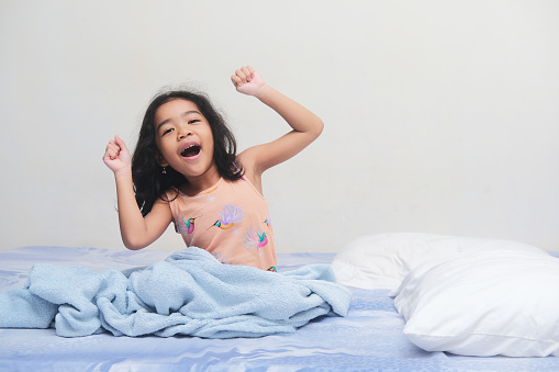 Asian kid girl wake up in the morning and showing cheerful expression