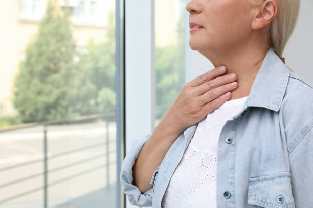 istock Mature woman doing thyroid self examination near window, closeup. Space for text 1392750254