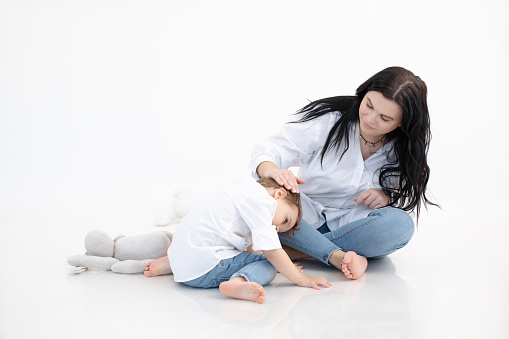 Woman and boy sitting together on floor, white background. Hugging and communicate, caring parent. Autism spectrum disorder concept, ASD. Mother and son autism problem. Child mental health concept.