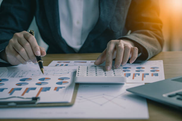 istock Businessman with pen pointing to graph, financial data, research, develop, market report. Strategic planning, analyzing, calculating financial accounts with calculator and laptop in the office. 1392753295
