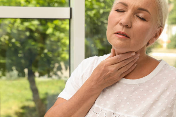 istock Mature woman doing thyroid self examination near window, closeup. Space for text 1392753543