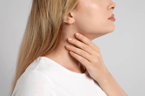 istock Young woman doing thyroid self examination on light grey background, closeup 1392753860