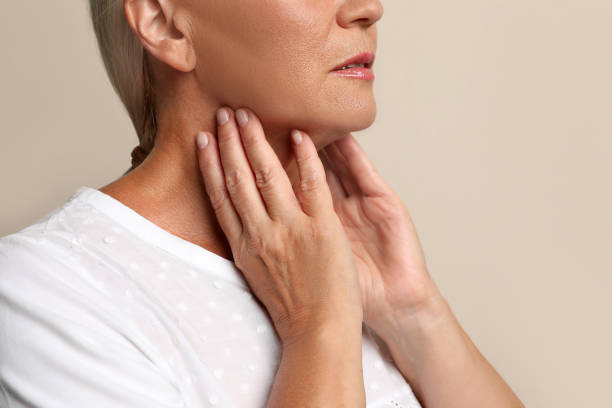 istock Mature woman doing thyroid self examination on beige background closeup 1392754697