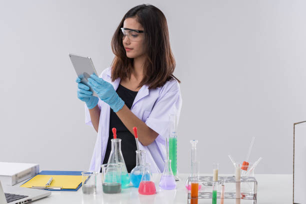 alegre mujer química en regazo, o estudiante graduada en bata de laboratorio y trabajo de desgaste protetivo, comprobar y probar la química. - biotechnology student laboratory nurse fotografías e imágenes de stock