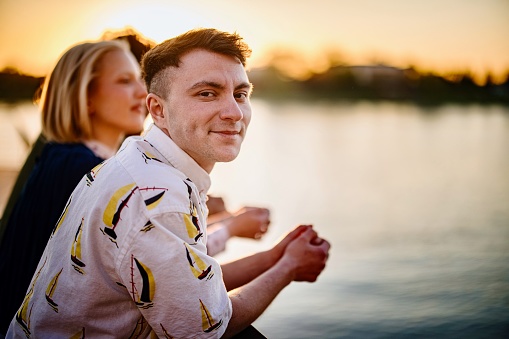 Portrait of a smiling young transgender man watching sunset with his friends