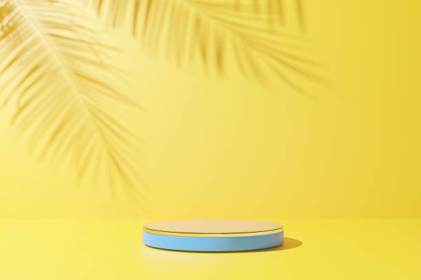 istock Blue glass podium and palm leaf shadow on yellow abstract background. 1392758803