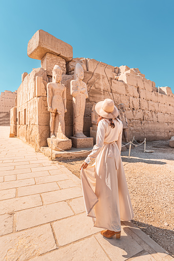 Woman traveler explores the ruins of the ancient Karnak temple in the city of Luxor in Egypt. Wanderlust and vacation