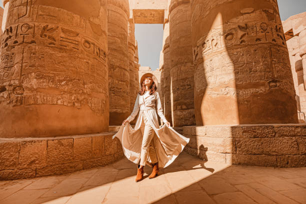 Woman traveler explores the ruins of the ancient Karnak temple in the city of Luxor in Egypt. Great row of columns with carved hieroglyph stock photo