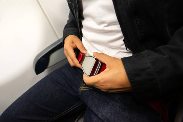 istock Man passenger fastening seat belt while sitting on the airplane. 1392760141
