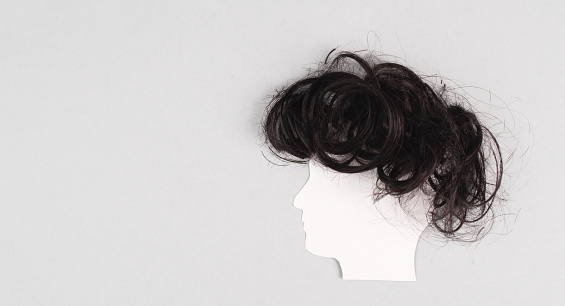 Silhouette of a face with a hairstyle, woman, man, transgender, copy space for text, portrait with dark hair, paper cut out
