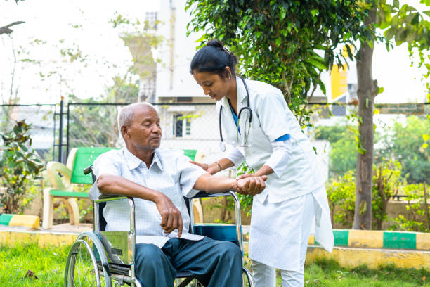 istock Doctor helping senior old patient to stretch hands during morning exercise while on wheelchair at hospital park - concept of physio, caretaker and therapy or treatment. 1392761813