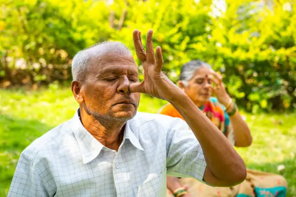 Photo of Close up shot of senior man doing nostril breathing exercise during morning at park - concept of healthy lifestyle, exercising and wellness