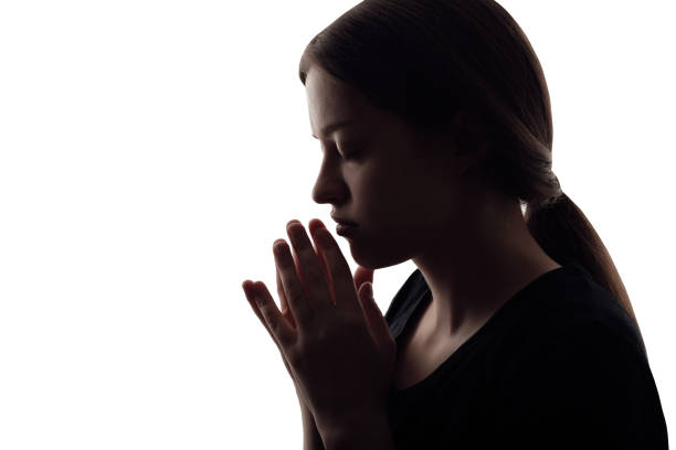 istock Woman's silhouette with folded her arms to pray on white background 1392762441