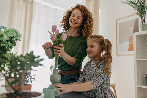 Mother and daughter putting pink tulips in the vase