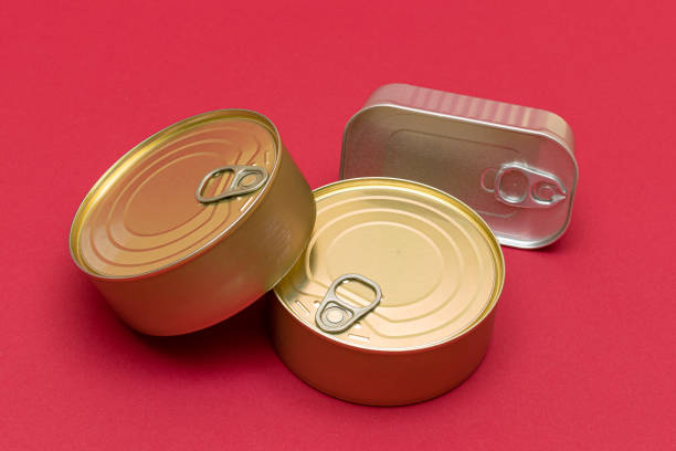 A Group of Stacked Tin Cans with Blank Edges on Red Background. Canned Food. Different Aluminum Cans for Safe and Long Term Storage of Food. Steel Sealed Food Storage Containers