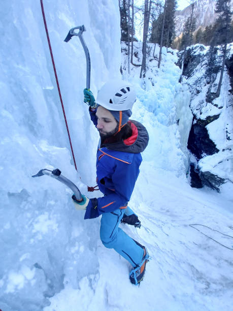 istock Young man ice climbing on frozen waterfall, he uses ice axes 1392768815