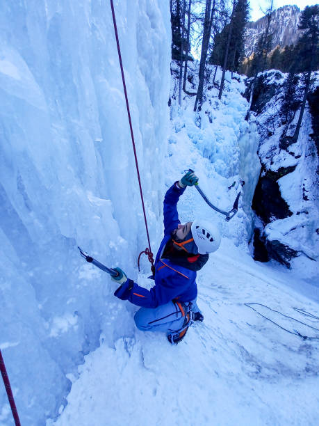 istock Young man ice climbing on frozen waterfall, he uses ice axes 1392768841