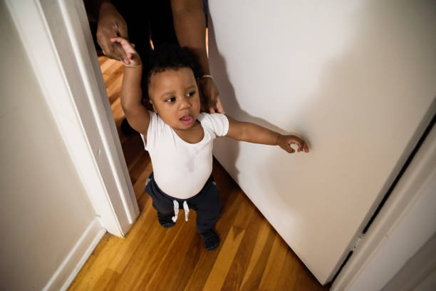 Cute baby boy escorted out of a room. Baby is one year’s old and has just learn how to walk. Horizontal indoors shot with soft focus. Copy space.