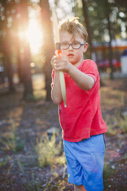 istock Young boy prepares bow and arrow in forest 1392772220