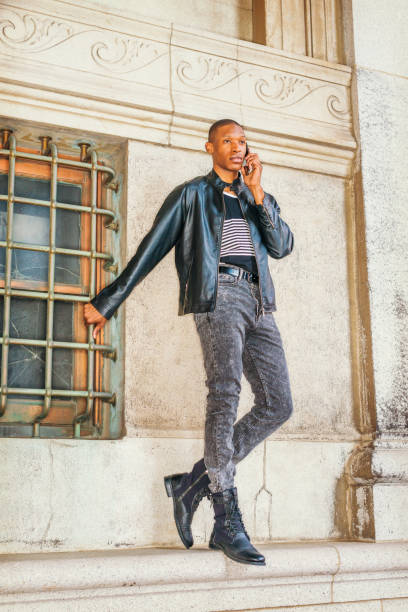 un jeune homme noir parle au téléphone portable à l’extérieur à new york - human leg jeans converse shoe photos et images de collection
