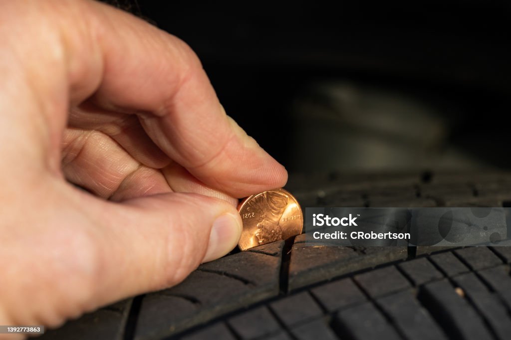 Checking tread depth on a tire by using a penny Using a penny to check tread depth on a tire Tire - Vehicle Part Stock Photo