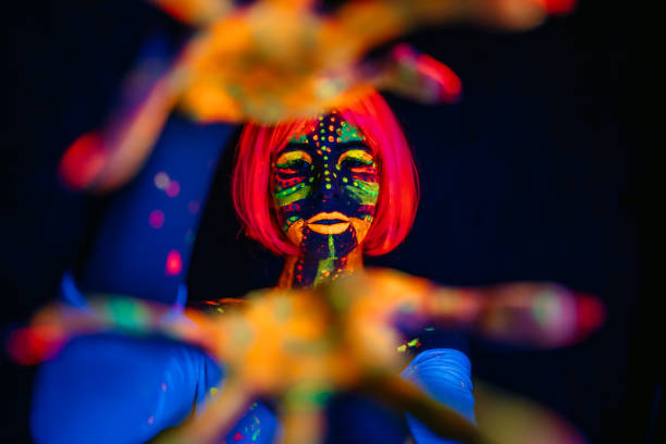 Portrait of a beautiful young woman wearing fluorescent makeup. Hands reaching out.