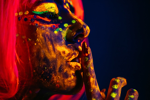 Portrait of a beautiful young woman wearing fluorescent makeup.