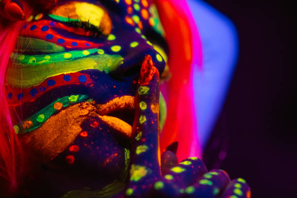 Portrait of a beautiful young woman wearing fluorescent makeup. Her eyes are closed. Close-up.