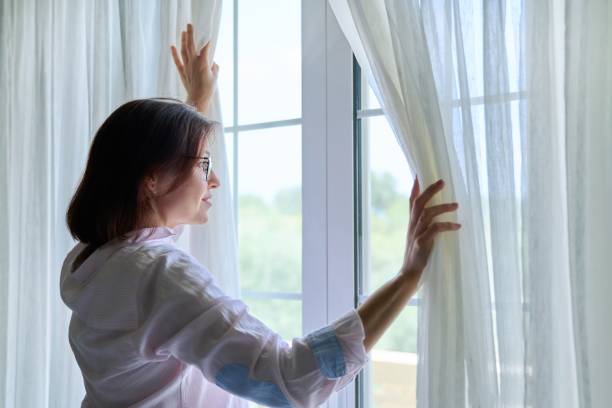 istock Smiling positive mature woman looking out the window 1392784331