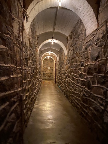 Long dimly lit stone hallway with an arrow at the end pointing to the left