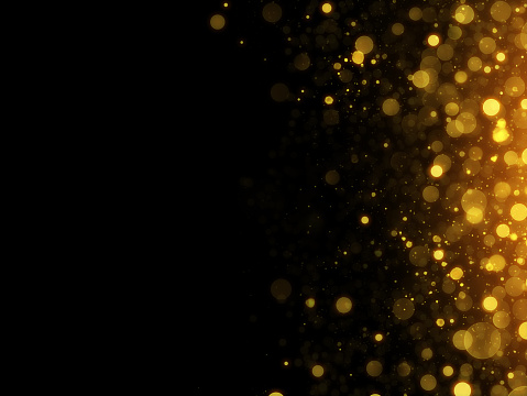 abstract unfocused black background with gold particles on the side and space for text
