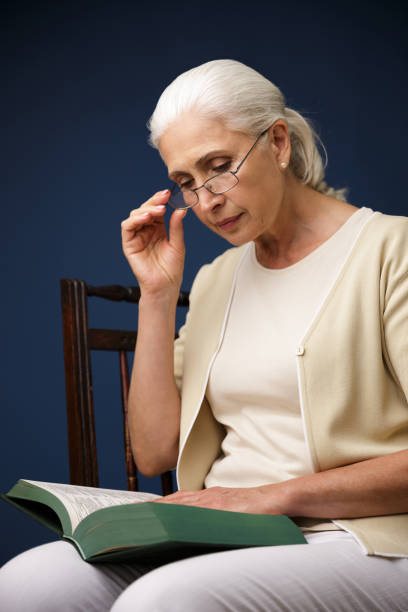istock Serious old woman sitting over dark blue background 1392788850