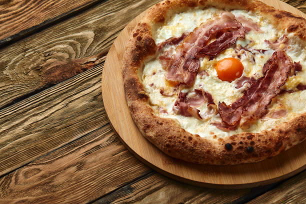 istock Carbonara pizza with bacon and egg on wooden background 1392789767