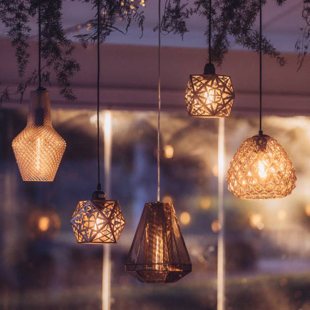 Square image Various golden shining illuminated lounge lights hanging together at dusk