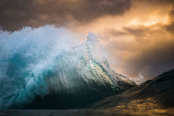 istock Powerful wave crashing out at sea underneath a golden sunset sky 1392793545