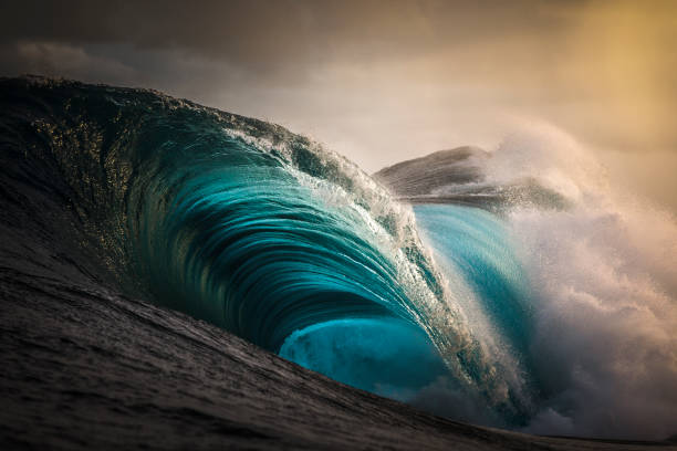 istock Smooth blue ocean wave crashing in golden light 1392793556