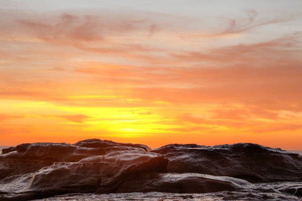 Gold and yellow sunset behind coastal rocks